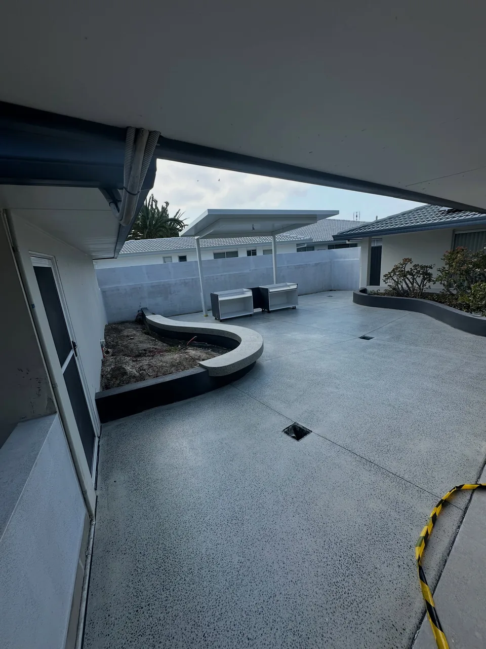 Honed and sealed concrete entertaining area beside a curved garden bed