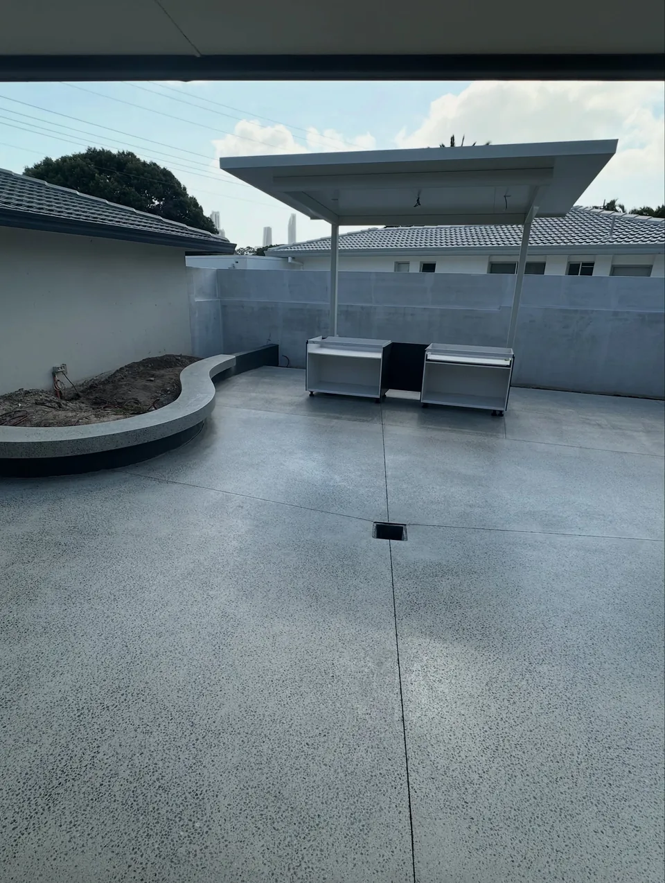 Completed honed and sealed concrete courtyard with an outdoor barbecue area