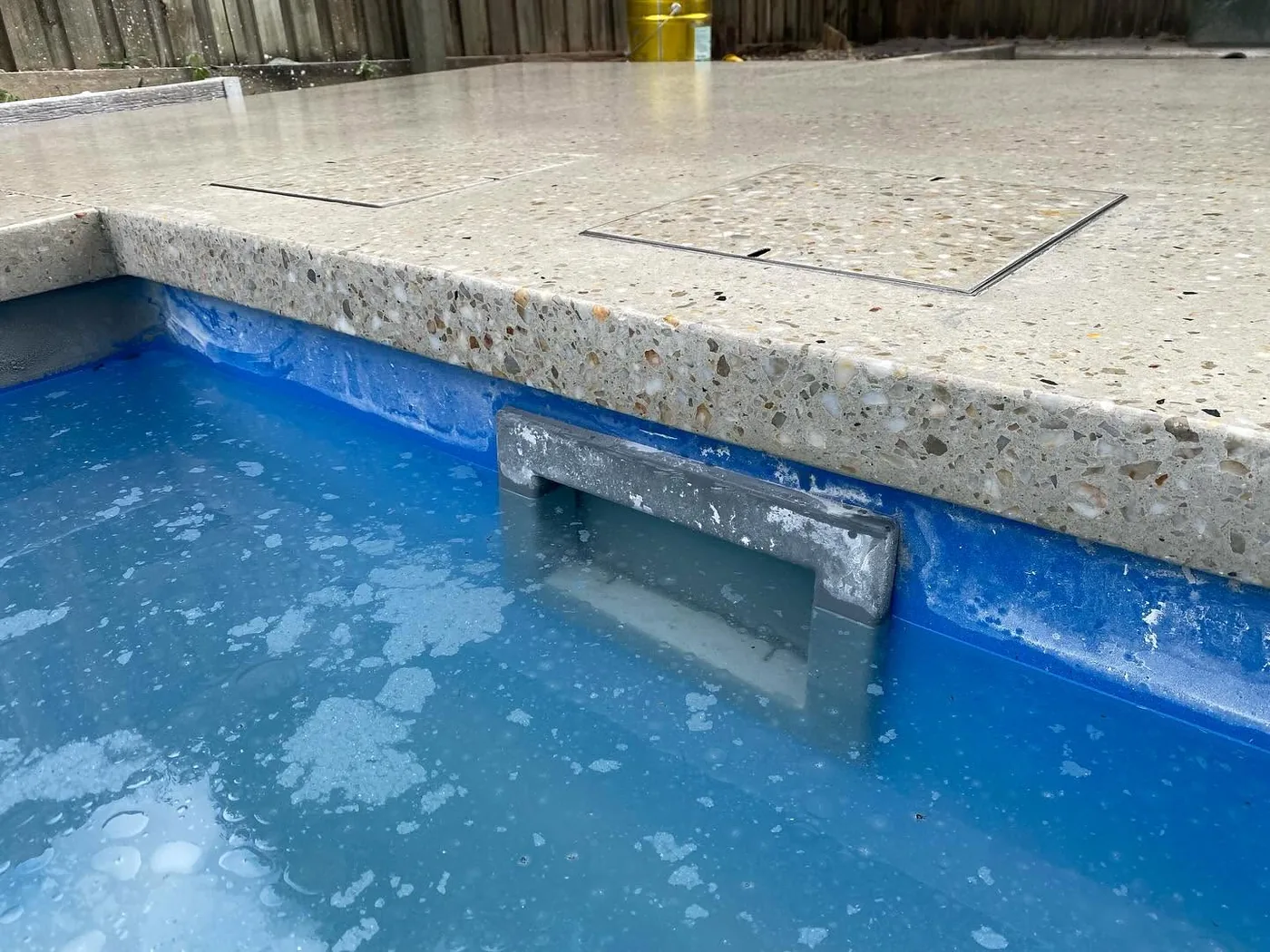 Exposed aggregate concrete detail beside a pool